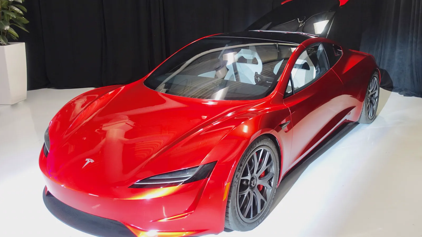 Prototype rouge de la Tesla Roadster de deuxième génération exposé en intérieur, portes ouvertes, vu de trois quarts avant